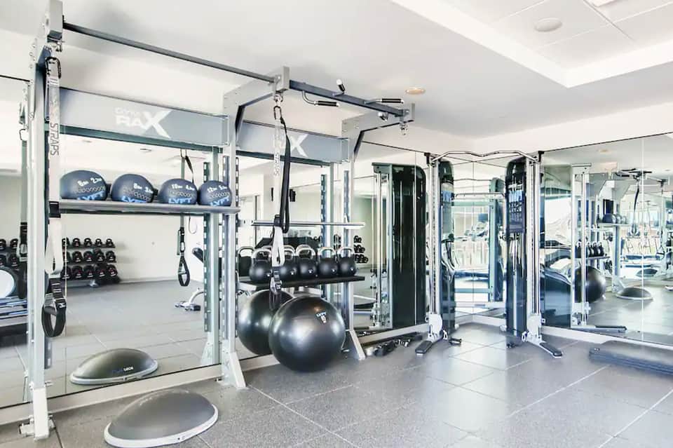 Modern fitness center with cable machines, dumbbells, exercise balls, and mirrored walls