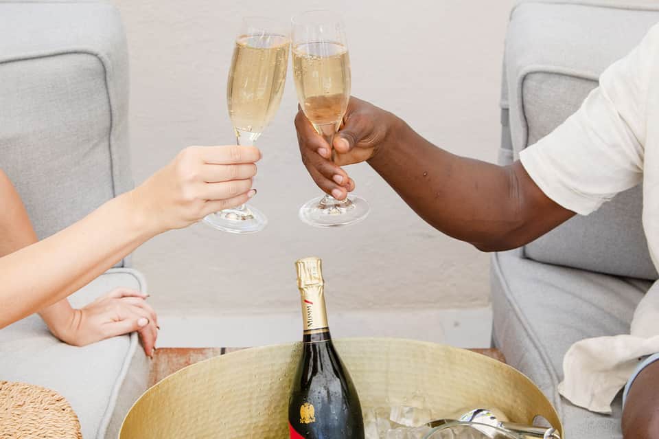 Two people toasting with champagne glasses over a bottle in an ice bucket