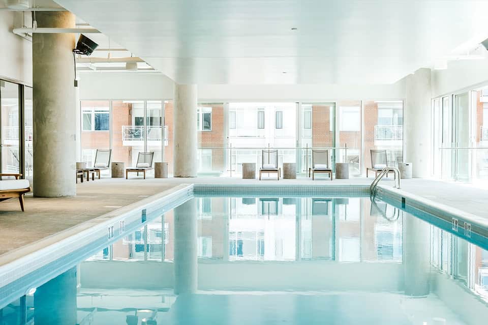 Indoor lap pool in bright, modern facility with concrete columns and large windows