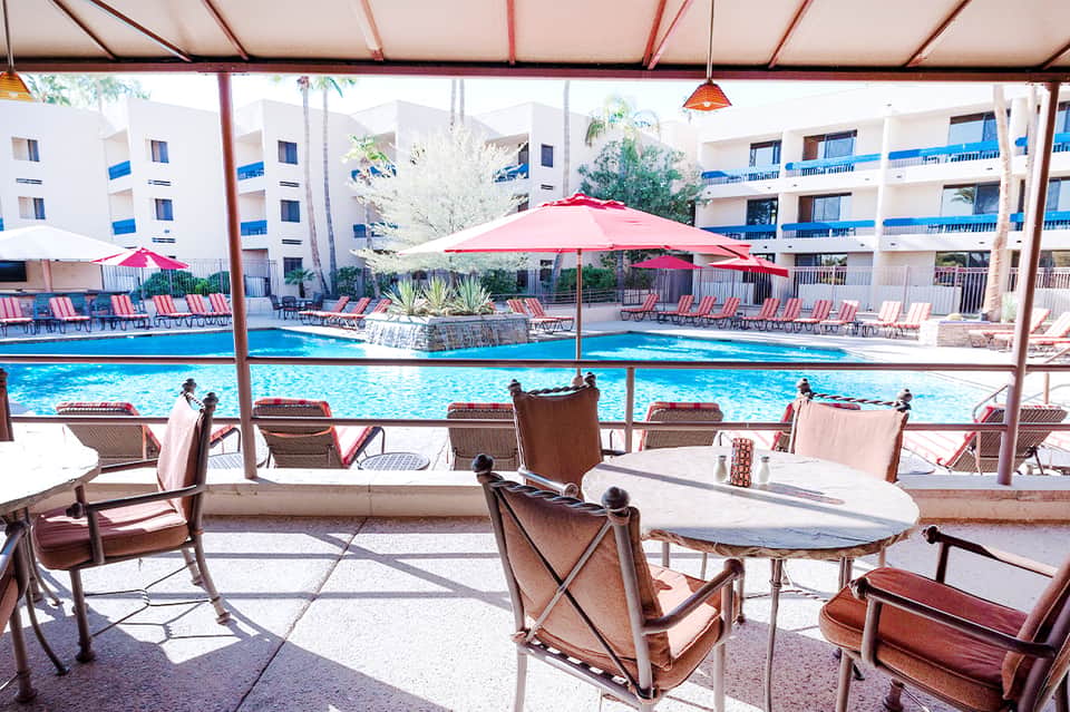 Resort pool area with pink umbrellas, loungers, and multi-story hotel building