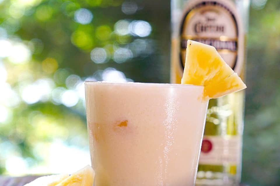 Refreshing citrus cocktail with lemon garnish and beer bottle in tropical outdoor setting