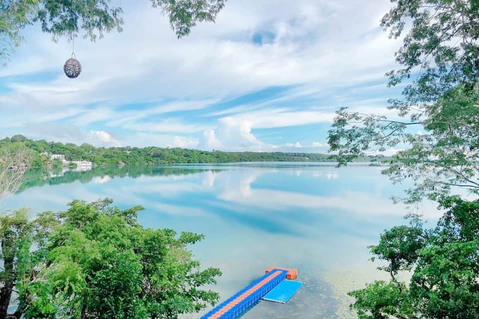 Serene lake with blue floating dock platform surrounded by lush green forest and mountains