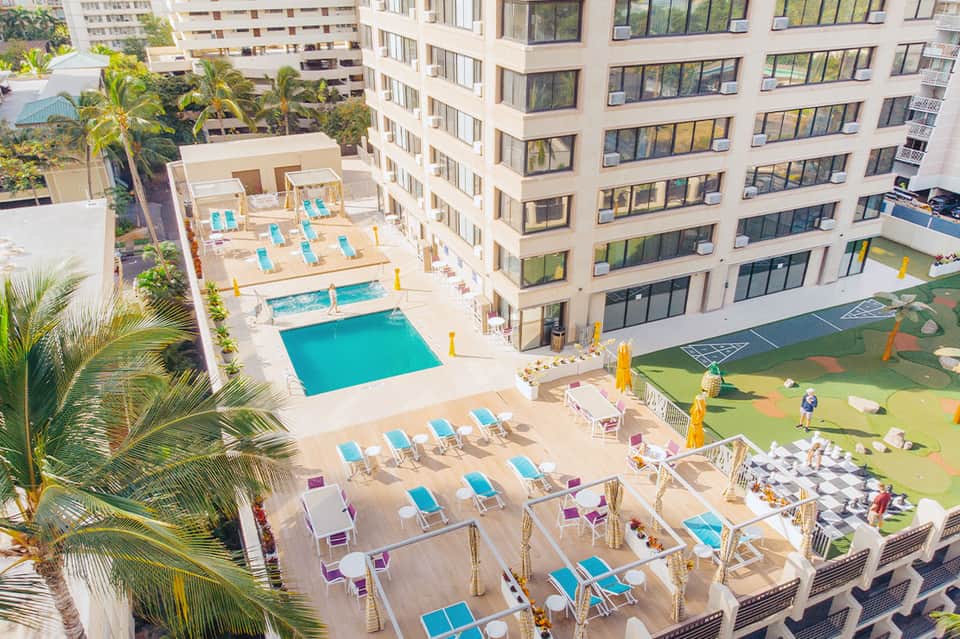 Resort courtyard with multiple pools, lounge chairs, and high-rise hotel buildings