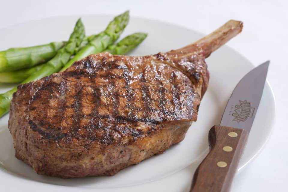 Grilled steak with asparagus on white plate with steak knife