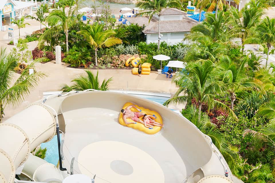 Aerial view of water slide facility surrounded by palm trees and beach area
