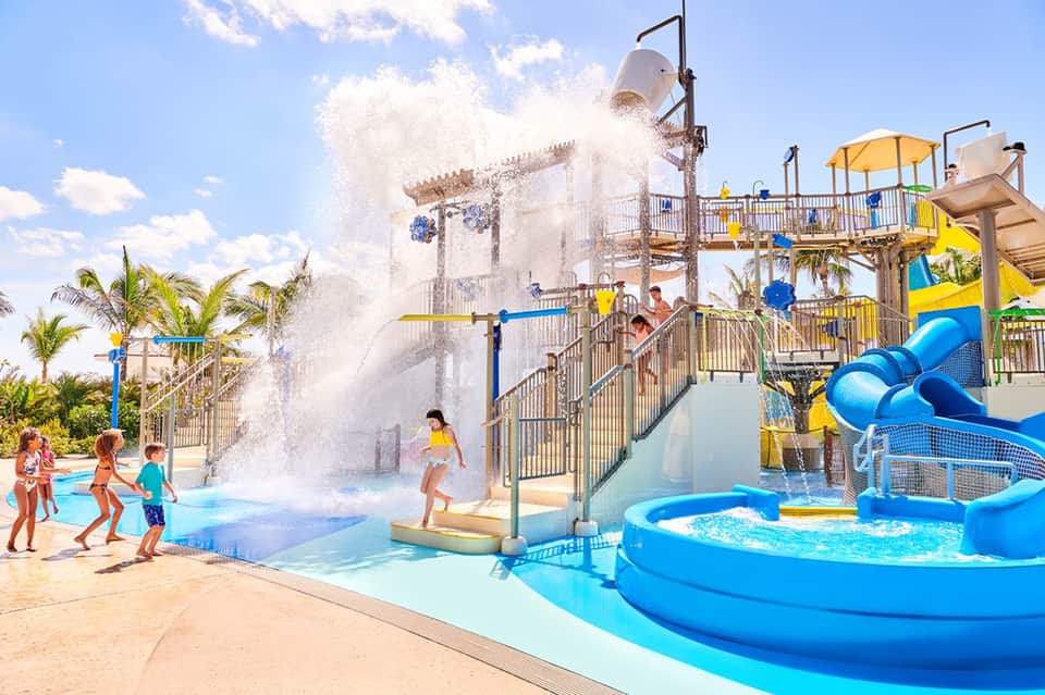 Children playing in splash pad with large water buckets at family-friendly water park resort