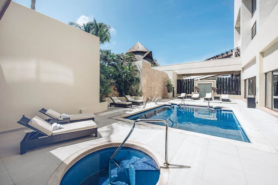 Modern resort courtyard with rectangular pool, lounge chairs, and white architecture