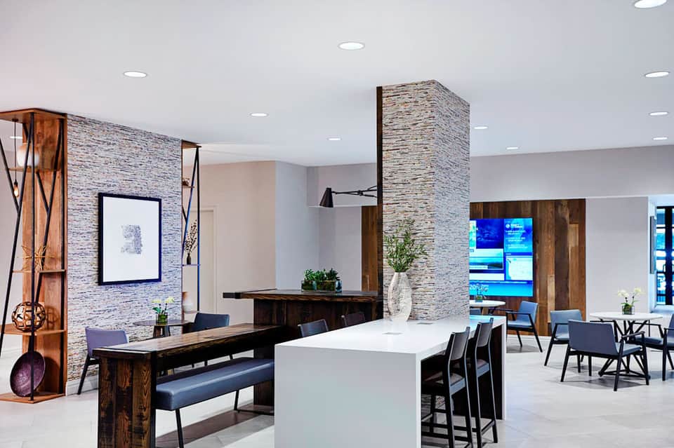 Contemporary hotel lobby with stone accent wall, wooden furniture, and modern seating areas
