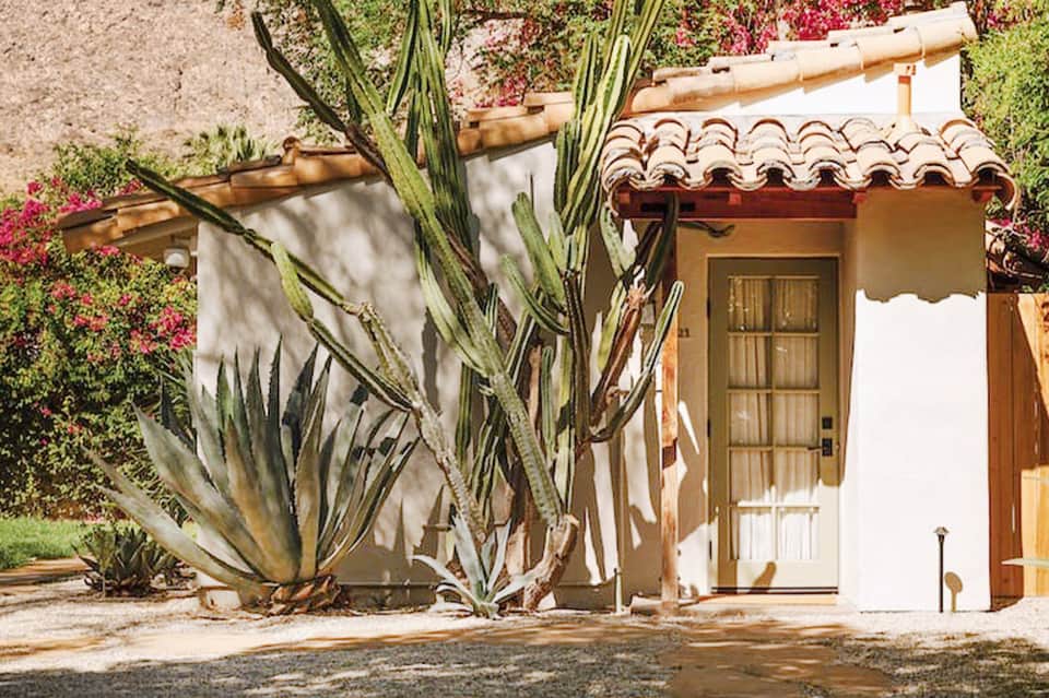 White Spanish colonial-style cottage with arched roof tiles, cactus plants, and magenta bougainvillea flowers