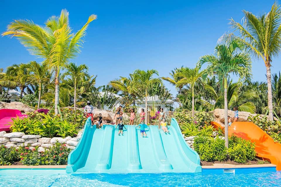 Colorful water slide complex with turquoise slides and palm trees at family resort pool