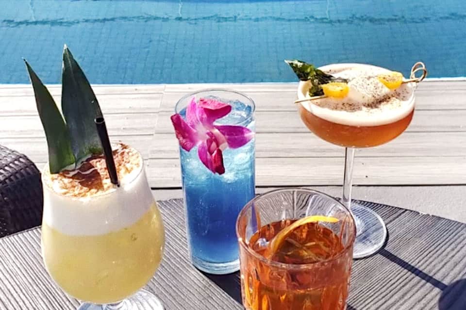 Tropical cocktails with decorative flowers, garnishes, and creative presentations served poolside