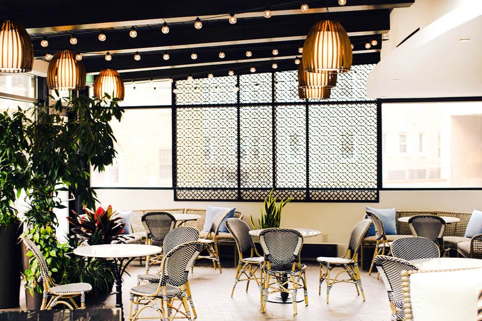 Contemporary restaurant interior with gold pendant lights, geometric screens, and dining tables