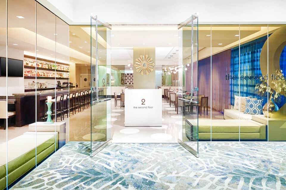Modern hotel lobby entrance with glass doors, elegant bar area, and contemporary furnishings