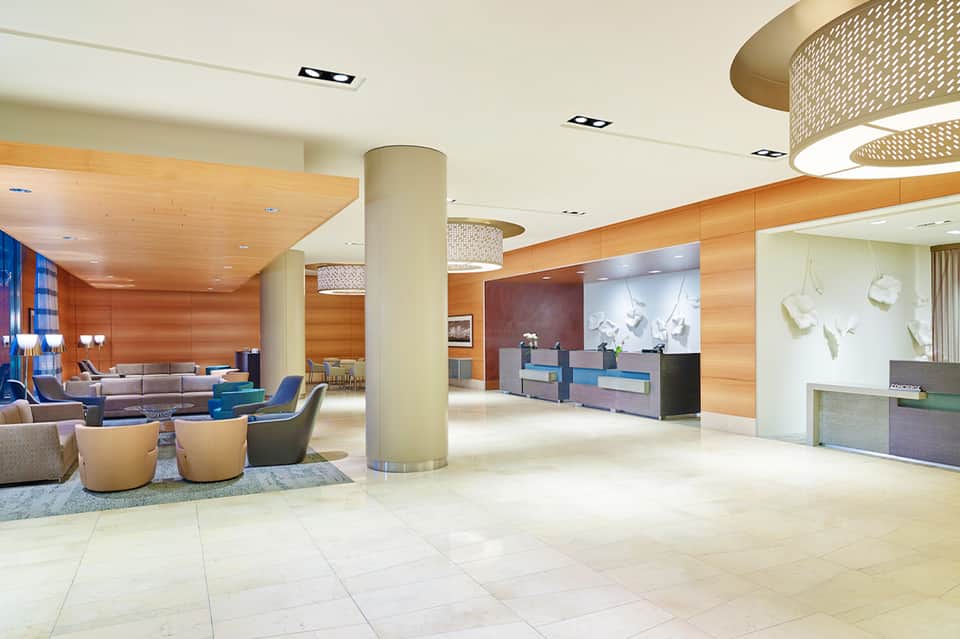 Modern hotel lobby with wooden accents, blue-purple desk, and contemporary seating area