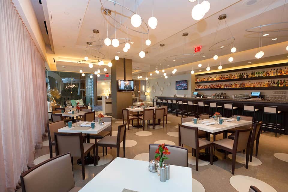 Contemporary restaurant dining room with hanging globe lights, bar, and table seating