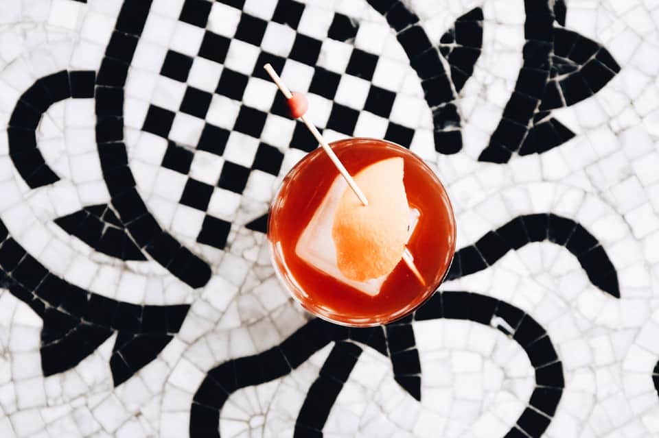 Cocktail with grapefruit slice on black and white geometric patterned tile poolside