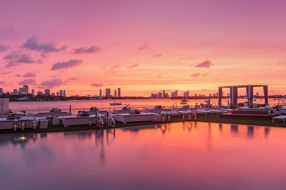 Sunset over waterfront with pink sky reflecting on calm water and modern marina docks