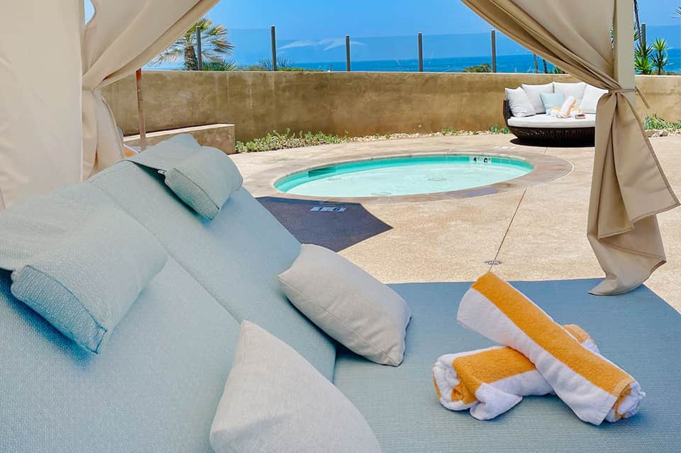 Private resort terrace with lounger, spa pool, and white curtain canopy overlooking ocean