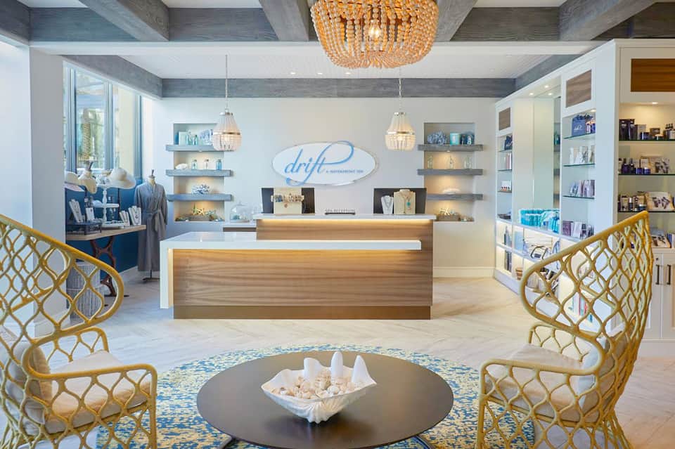 Modern spa reception desk with beige and blue tones, wooden accents, and gold pendant lighting fixtures