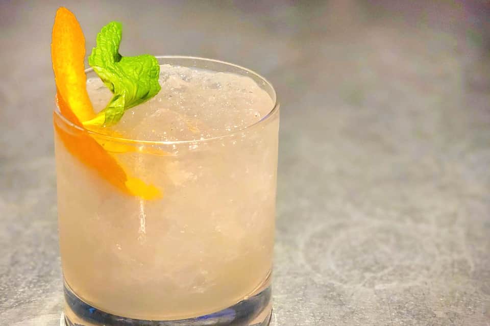 Tropical cocktail with citrus garnish and mint on concrete surface