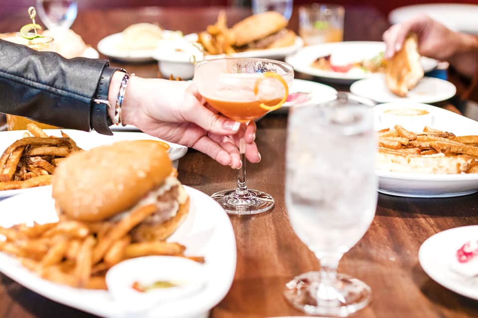 Diners enjoying burgers and fries at a restaurant table with beverages