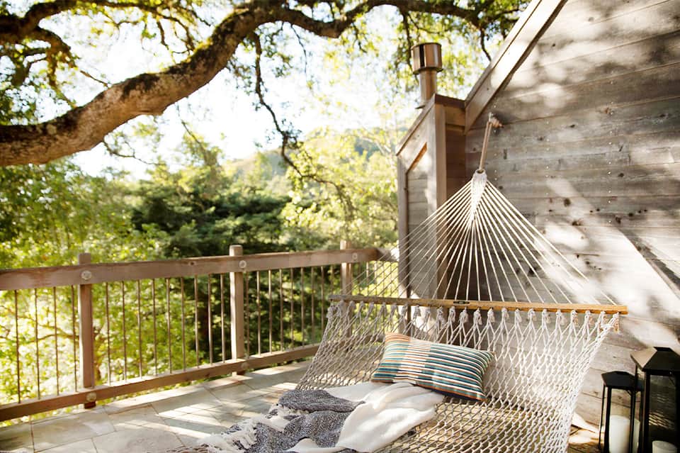 Backyard hammock on wooden deck with forest views and hanging cushions