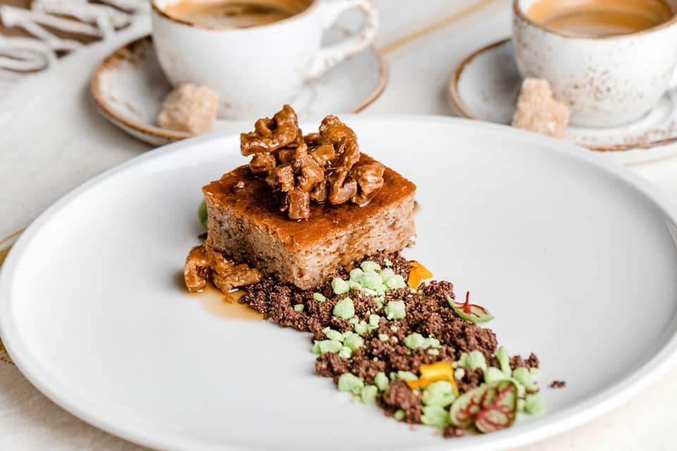 Gourmet dessert plate with walnut cake and chocolate garnish served with coffee cups
