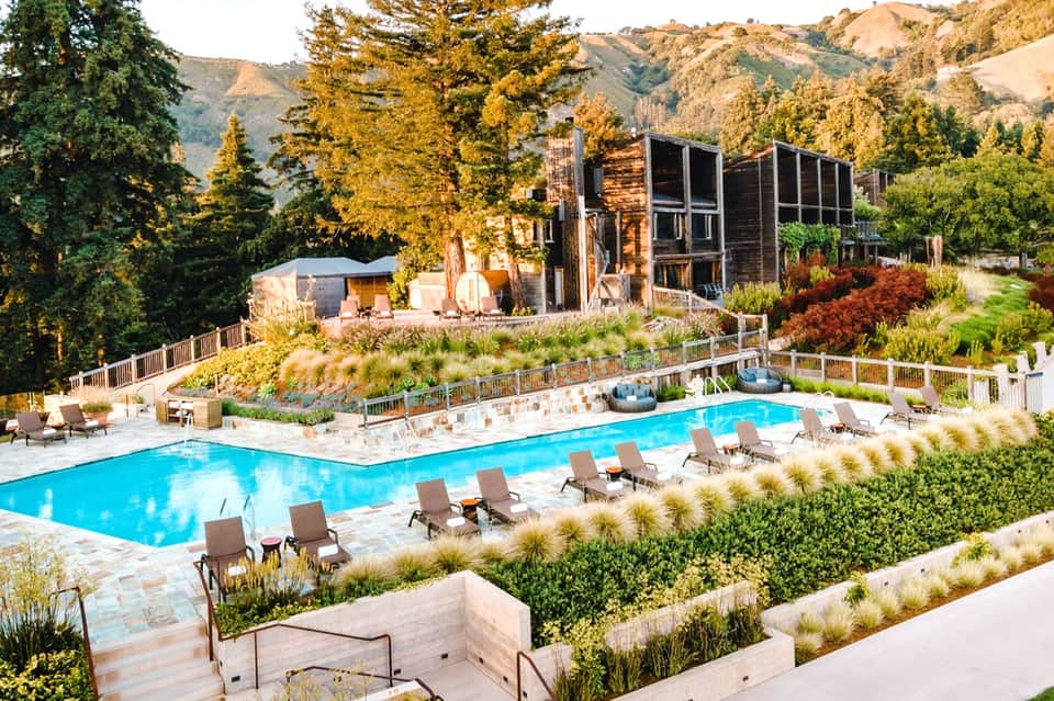 Mountain resort with pools, modern architecture, lounge chairs, and scenic valley views