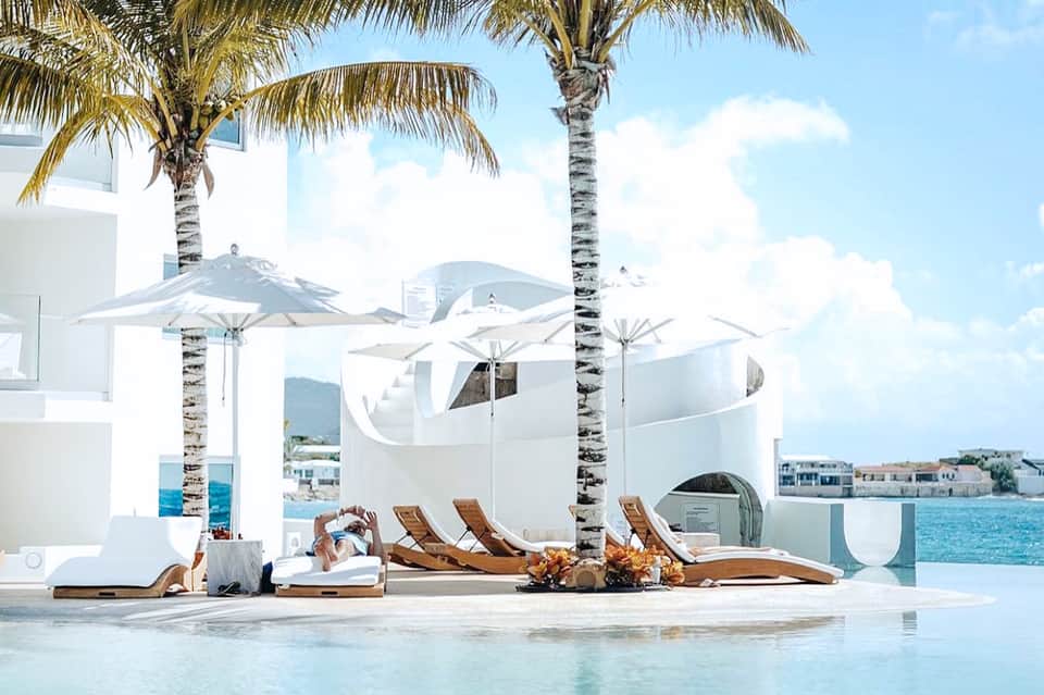 Beachfront resort seating area with white umbrellas, lounge chairs, and ocean view