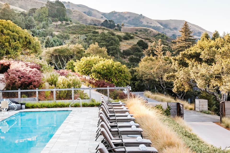 Mountain valley pool with lounge chairs and blooming trees at resort