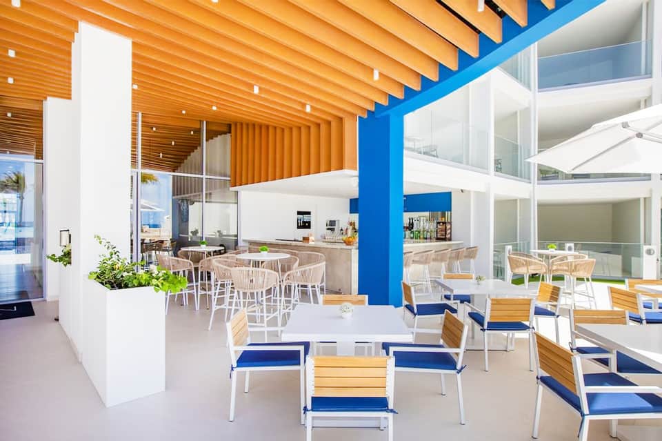 Modern resort dining area with wooden beams, blue accents, and ocean views