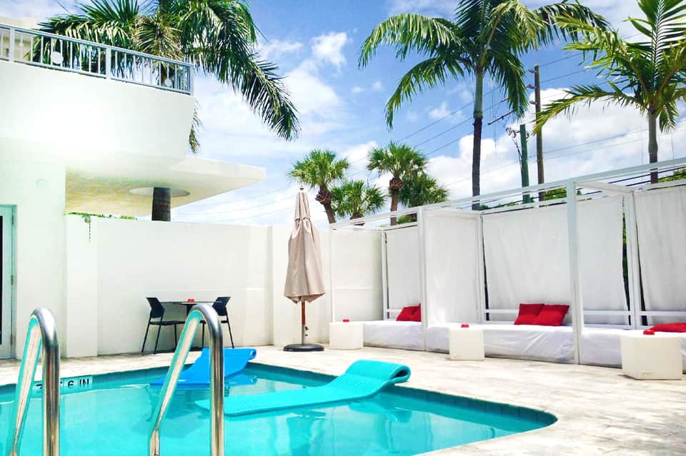 Modern pool area with white privacy screens, lounge beds, and turquoise water