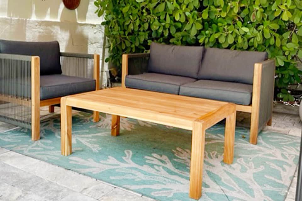 Outdoor patio with wooden table, gray cushioned seating, and green living wall backdrop