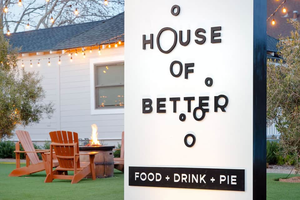 House of Better restaurant sign with firepit seating area and modern white building exterior