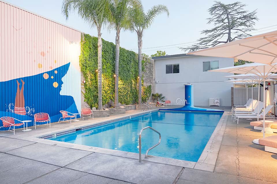 Contemporary resort pool with artistic blue sculpture, palm trees, and lounge seating
