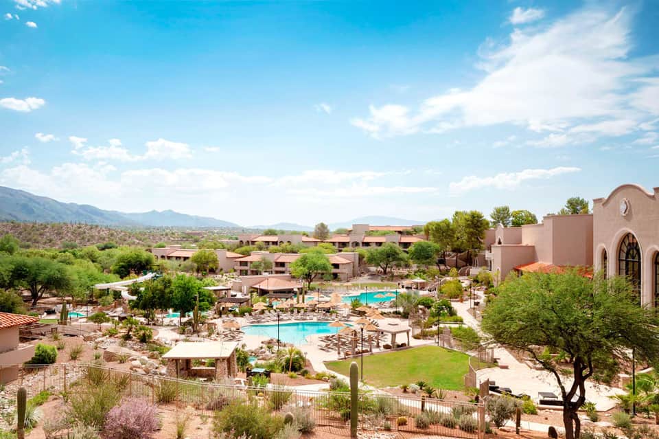 Desert resort with multiple pools, rustic buildings, and mountain landscape views