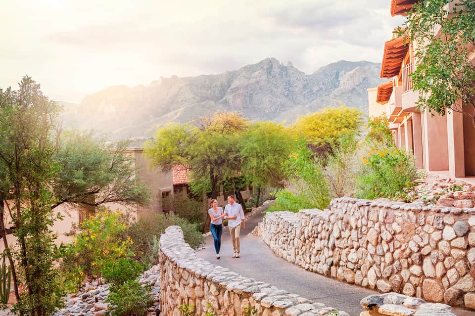 Mountain lodge courtyard with rustic stone pathways, Spanish colonial architecture, and lush vegetation