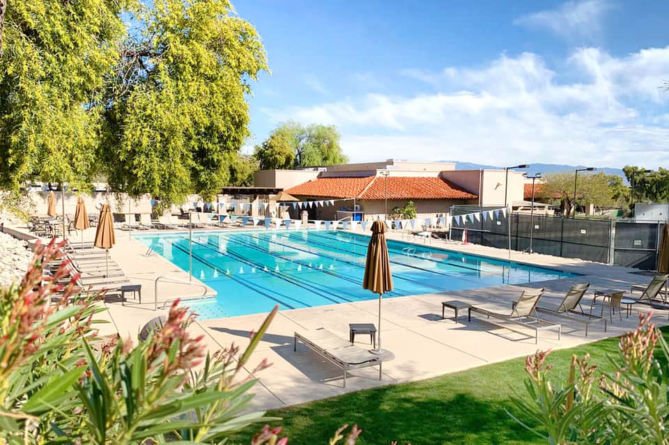 Outdoor swimming pool with lounge chairs, umbrellas, and landscaped surroundings
