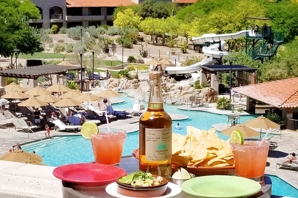 Colorful cocktails and appetizers on resort balcony overlooking pool and landscaped grounds