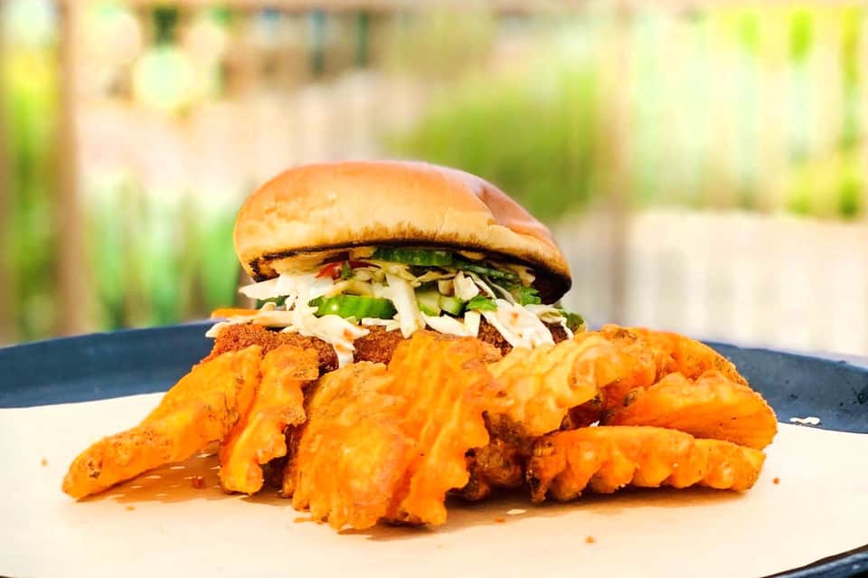 Gourmet burger with coleslaw and waffle fries on outdoor patio table