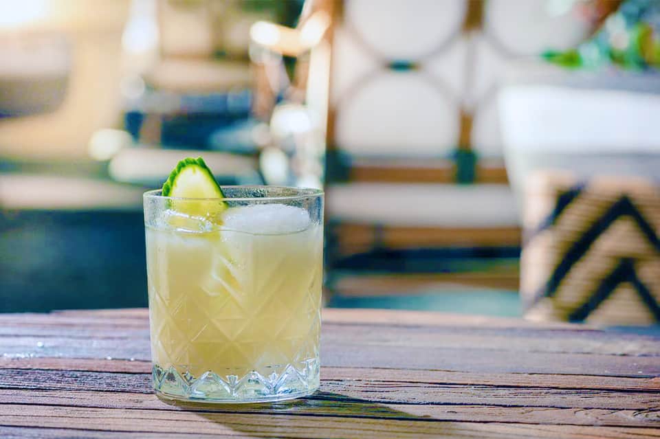 Refreshing citrus cocktail with lime garnish on wooden poolside table