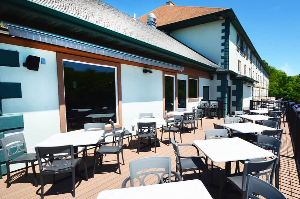 Outdoor dining terrace with white tables, black chairs, and modern building architecture