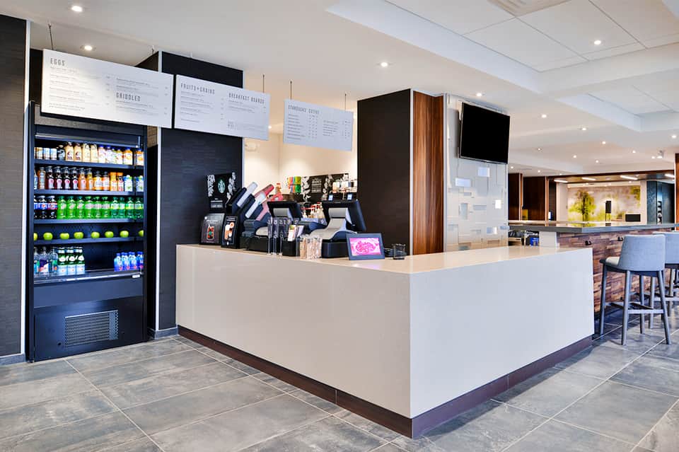 Hotel café counter with beverage cooler, menu boards, and service area with modern design