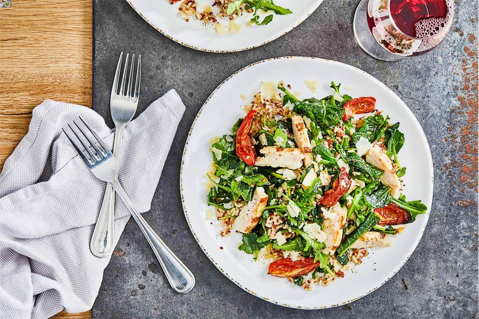 Fine dining table setting with green salad, forks, napkin, wine glass on textured gray surface