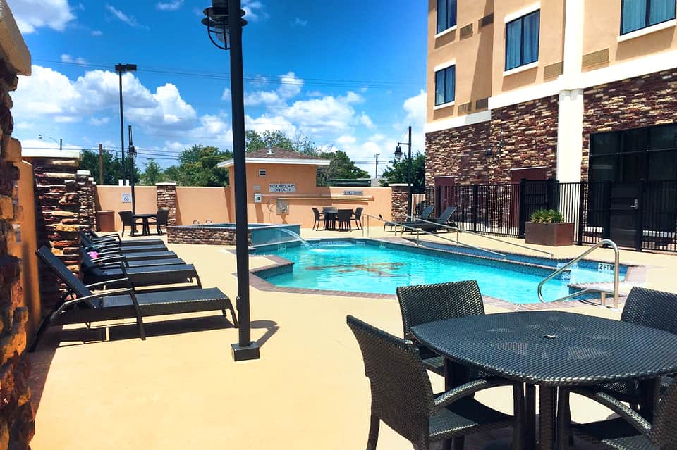 Resort pool area with lounge chairs, fire pit, and modern stone building