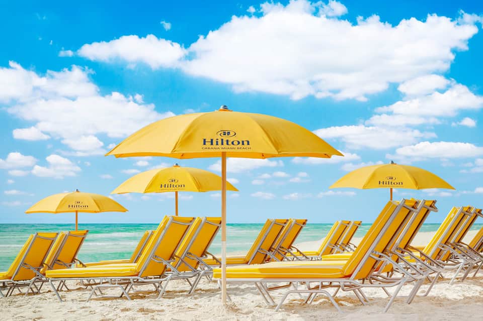 Beach lounge area with yellow umbrellas and chairs overlooking turquoise ocean water