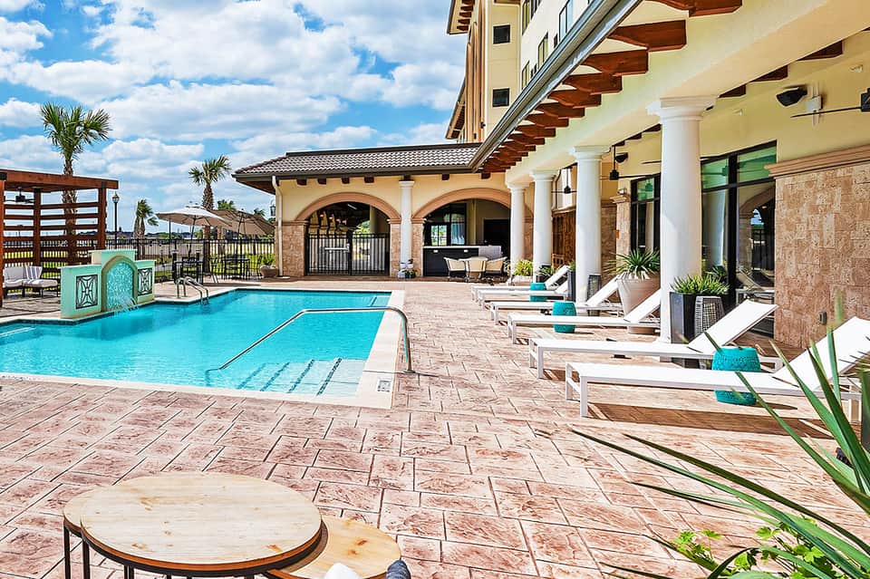 Luxury resort pool area with turquoise water, lounge chairs, covered pavilion, and manicured grounds