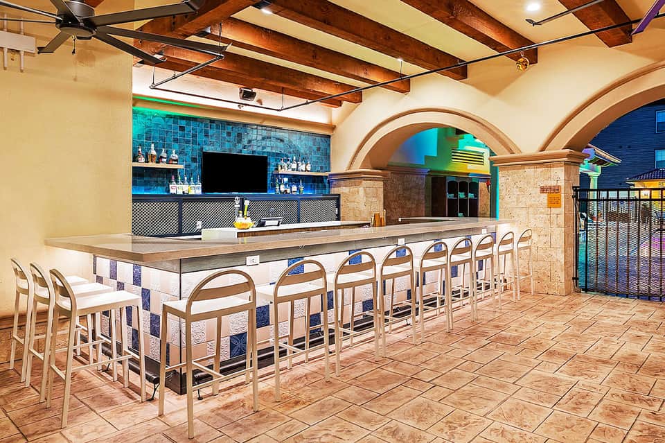 Modern bar lounge with turquoise tile backsplash, wooden ceiling beams, and arched architectural details