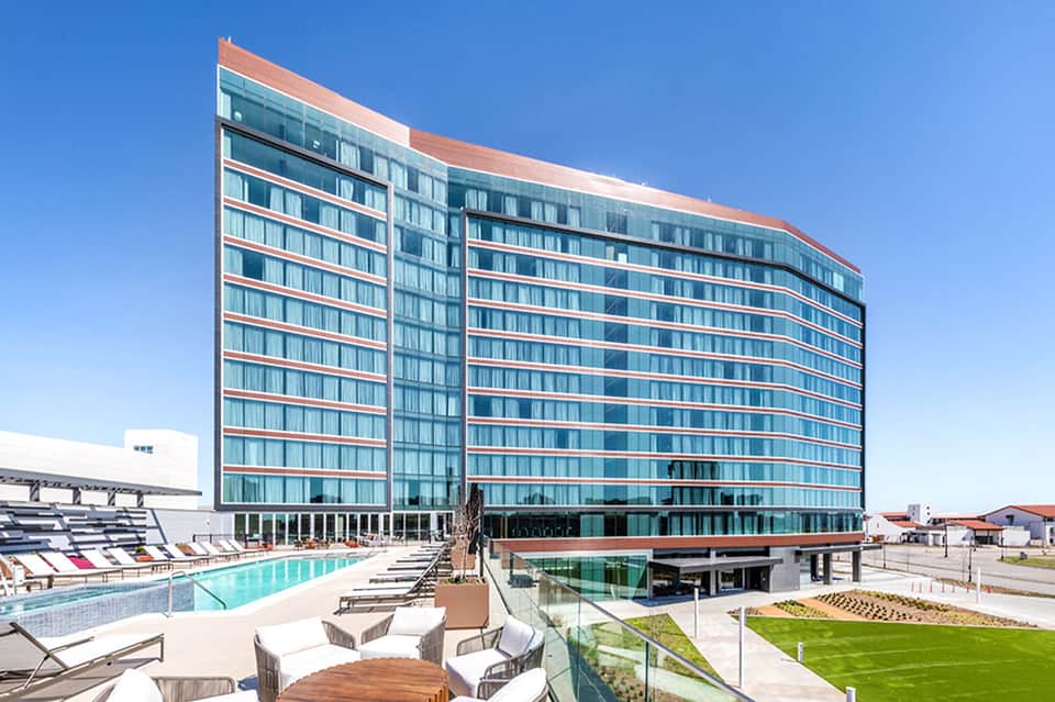Contemporary hotel building with curved glass facade and pool lounge area