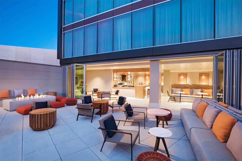 Modern outdoor terrace with contemporary seating, fire pit, and floor-to-ceiling glass doors